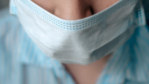 Girl surgeon doctor puts surgical mask on her face. Preparation for surgery, infection protection, quarantine, epidemic, medicine, virus, flu concept. Close-up top view